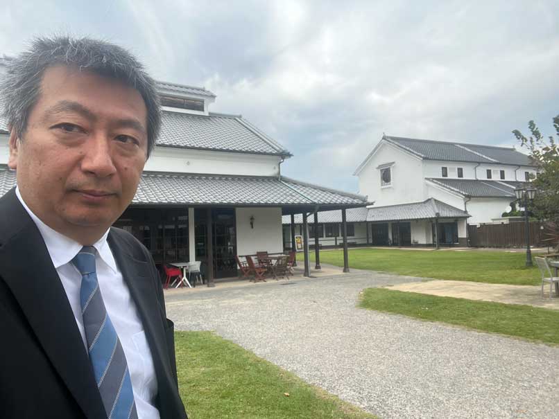 サーラ・デ・うすきの芝生の広場を背に立つ武蔵野市議会議員の藪原太郎